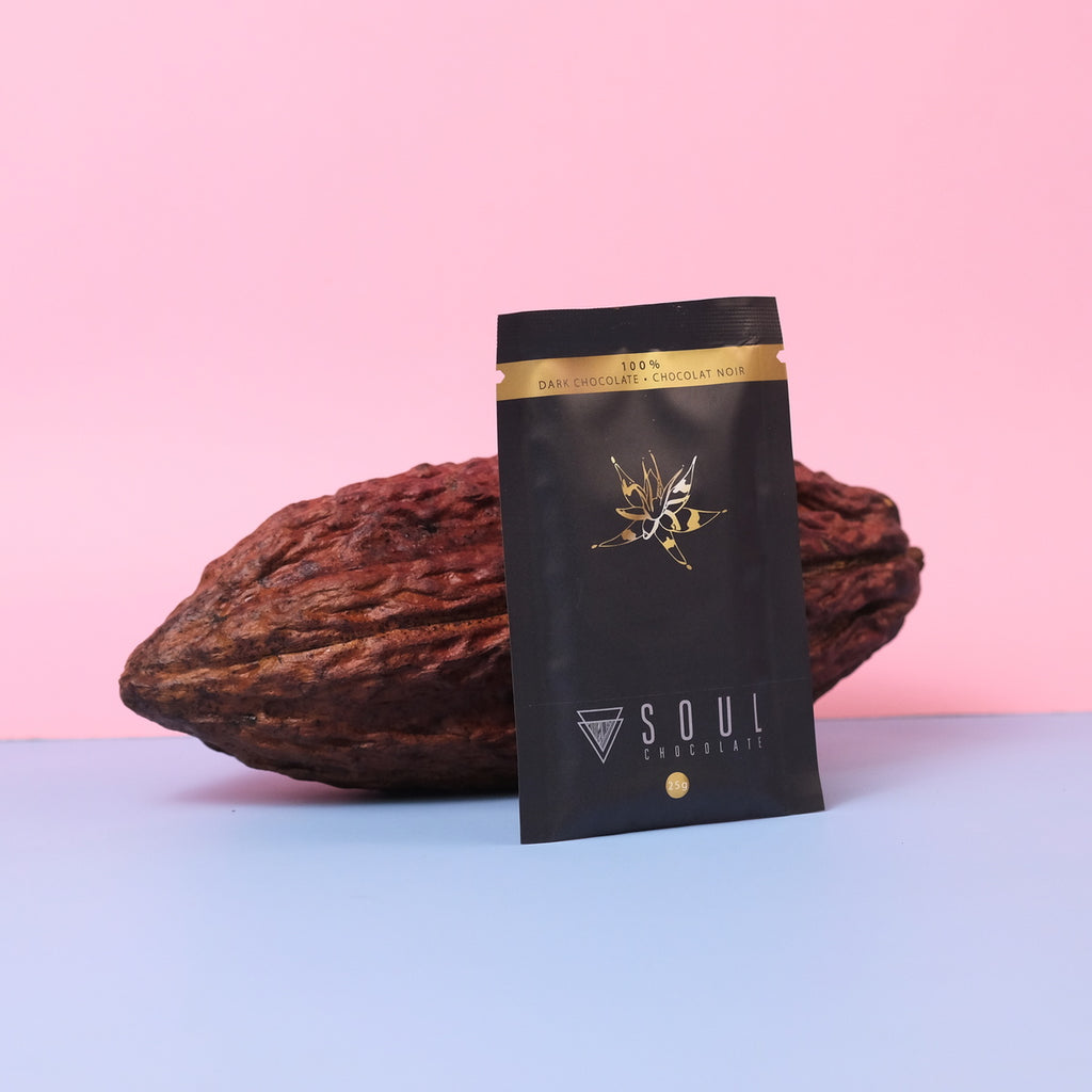 Dark chocolate bar packaging with cacao beans on a pink and blue gradient background