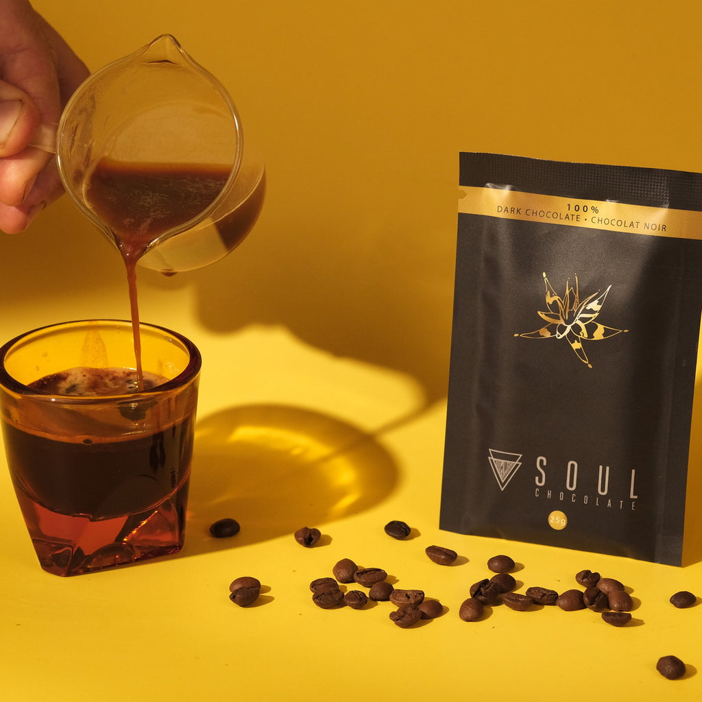 Soul Chocolate 100% dark chocolate from Colombia packaging with coffee beans and a glass of coffee on a yellow background