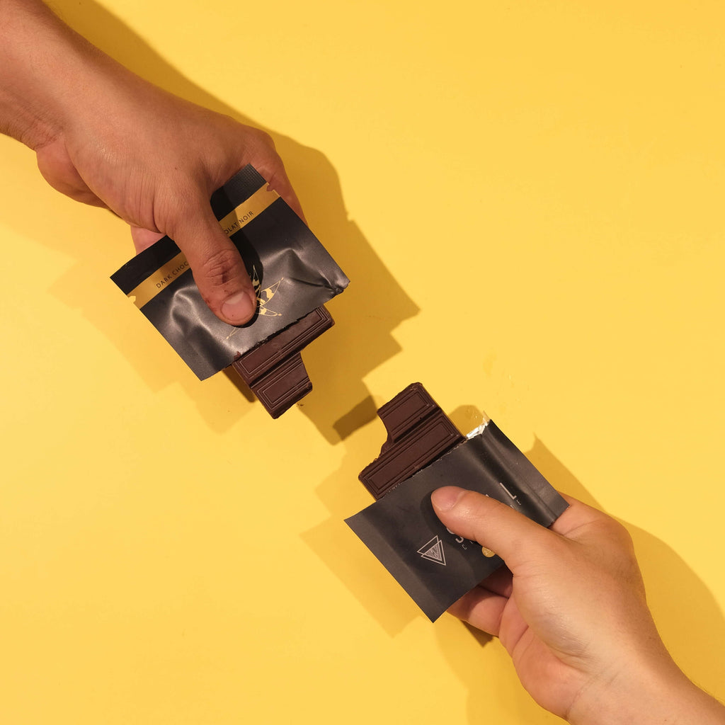 Two hands holding unwrapped 100% Colombian dark chocolate