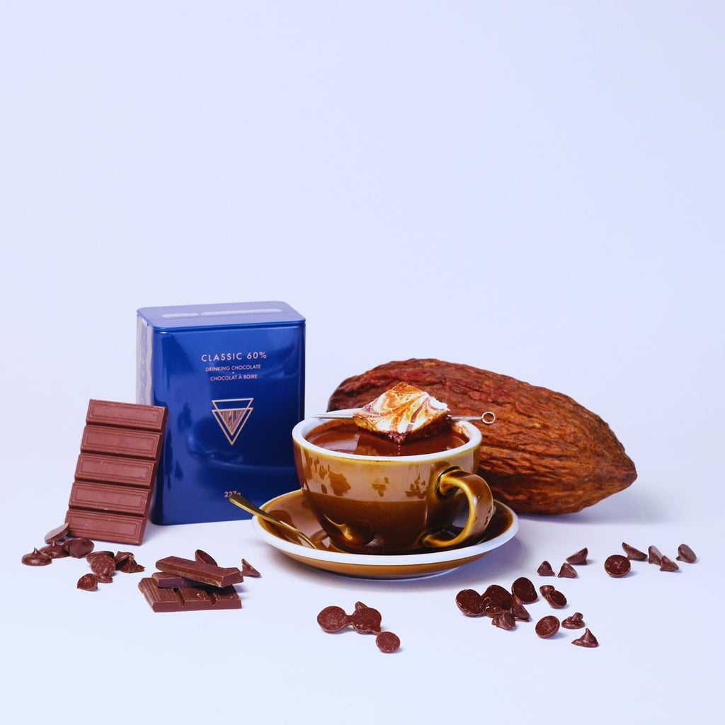 A shiny tin of classic hot chocolate cocoa with a mug of frothy hot cocoa with a marshmallow