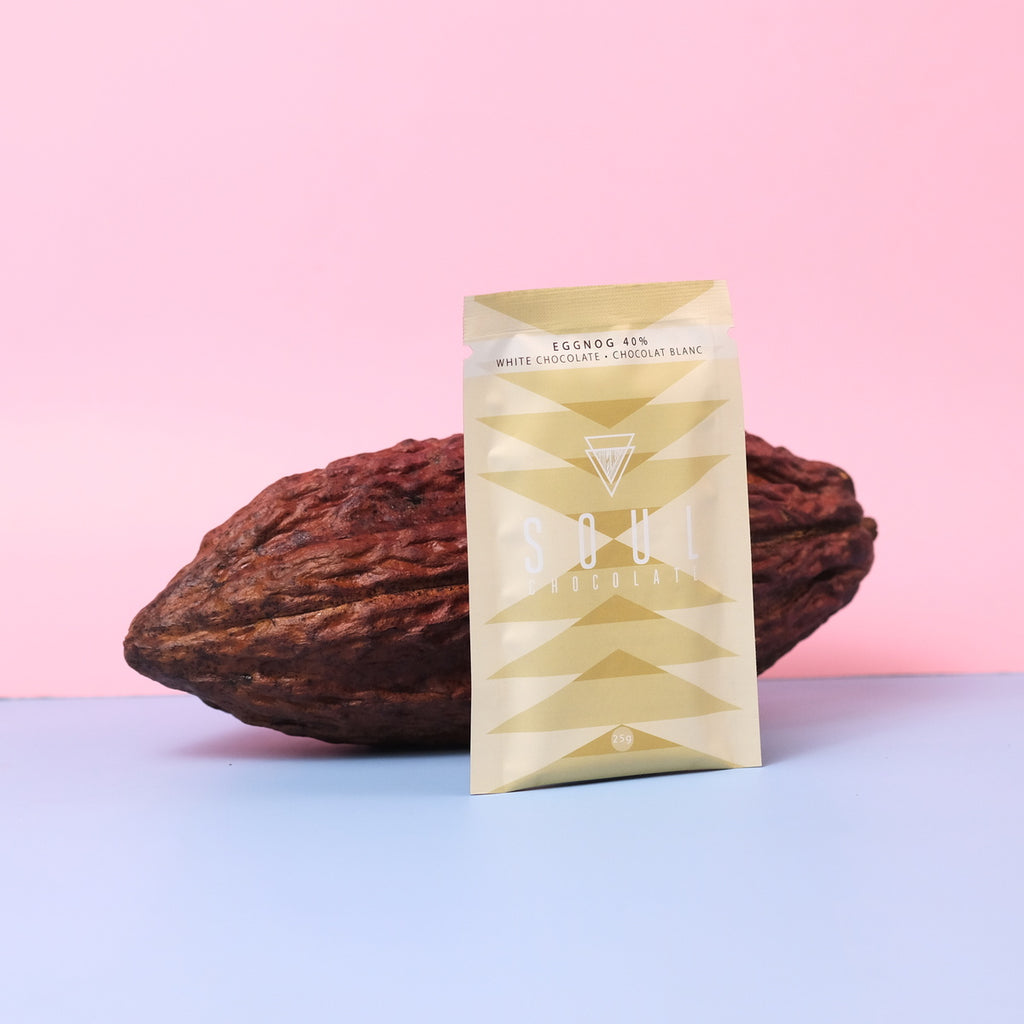 Gold packaged white eggnog chocolate resting on a cacao pod