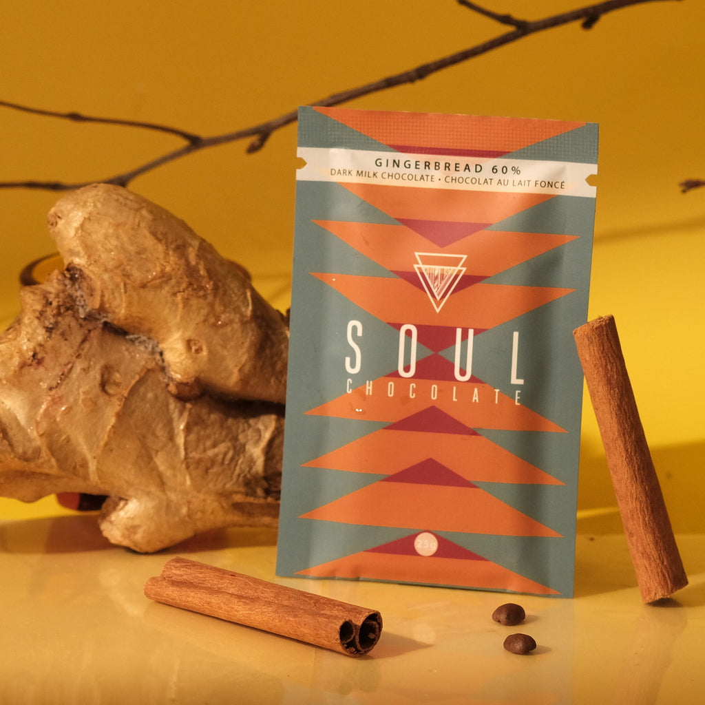 A gingerbread chocolate bar package alongside a hunk of ginger and cinnamon sticks