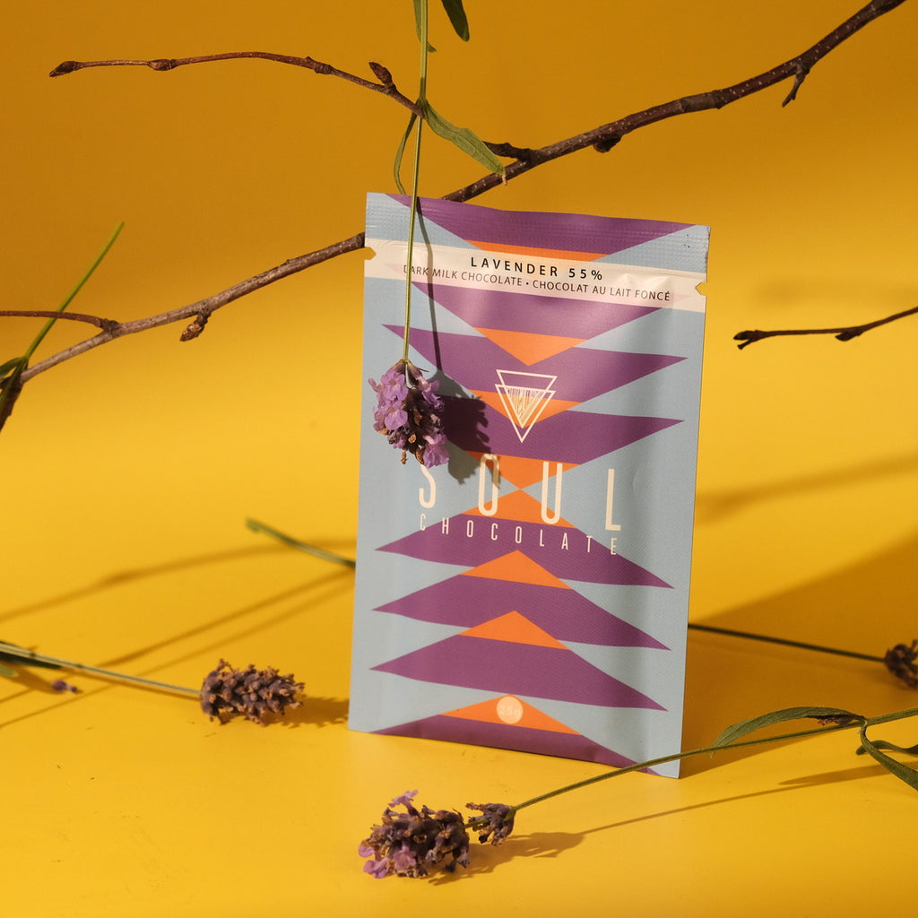 Lavender Soul Chocolate bar packaging surrounded by lavender sprigs on a yellow background