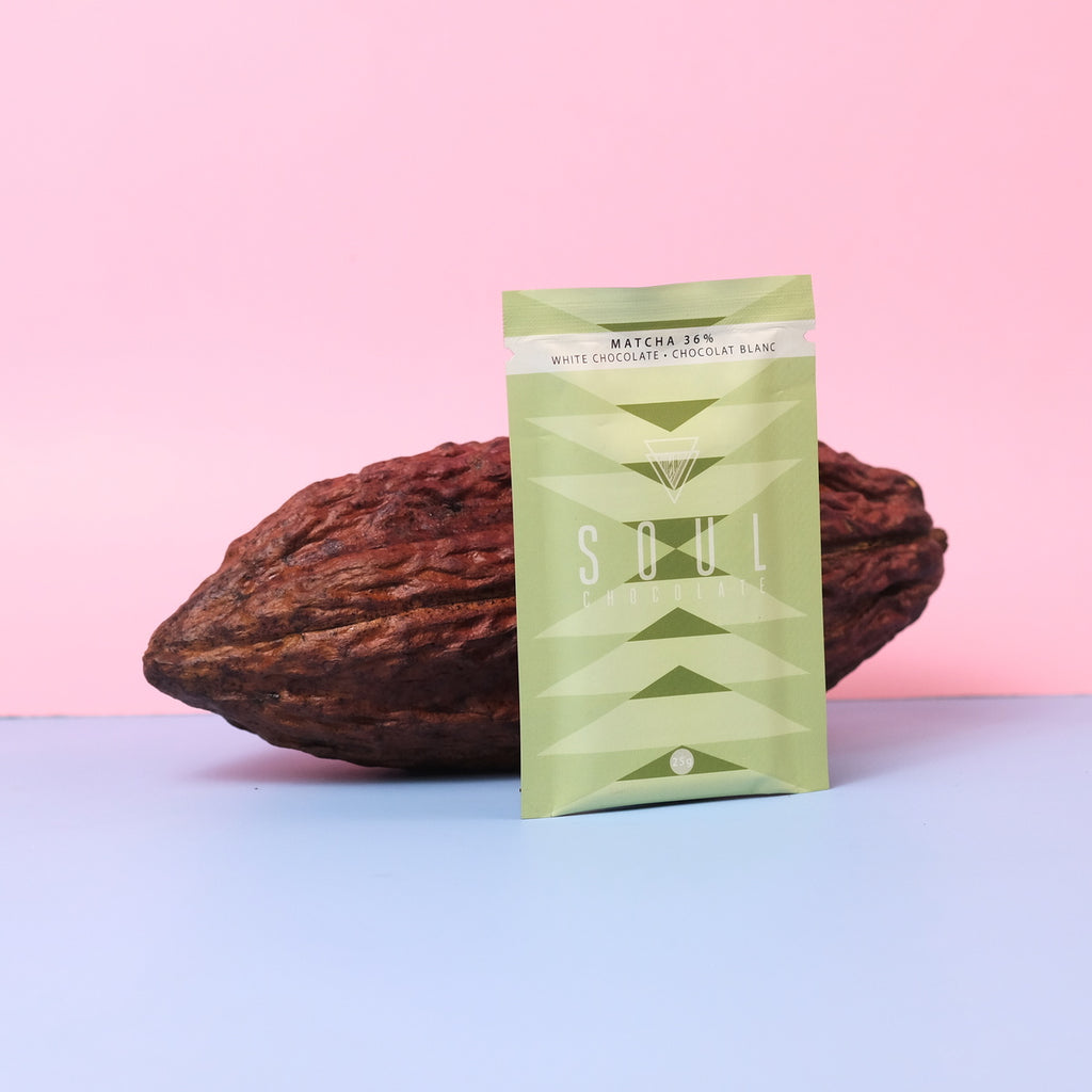 Green packaging of soul chocolate with a cocoa pod on a pink and blue gradient background