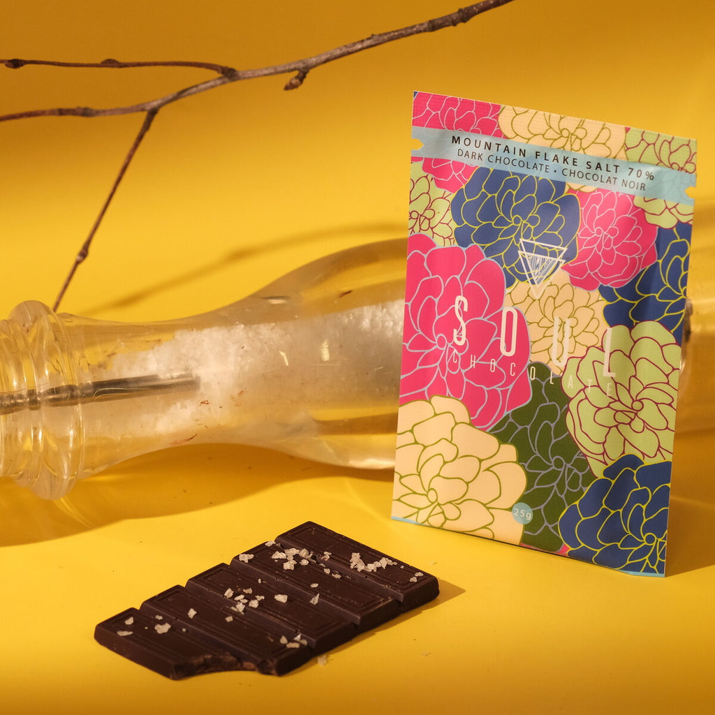 Flaked salt chocolate bar with a colorful floral packaging on a yellow background