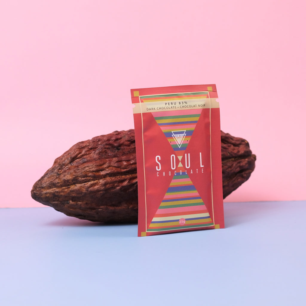 Soul Chocolate peruvian bar with a cacao pod on a pink and blue gradient background
