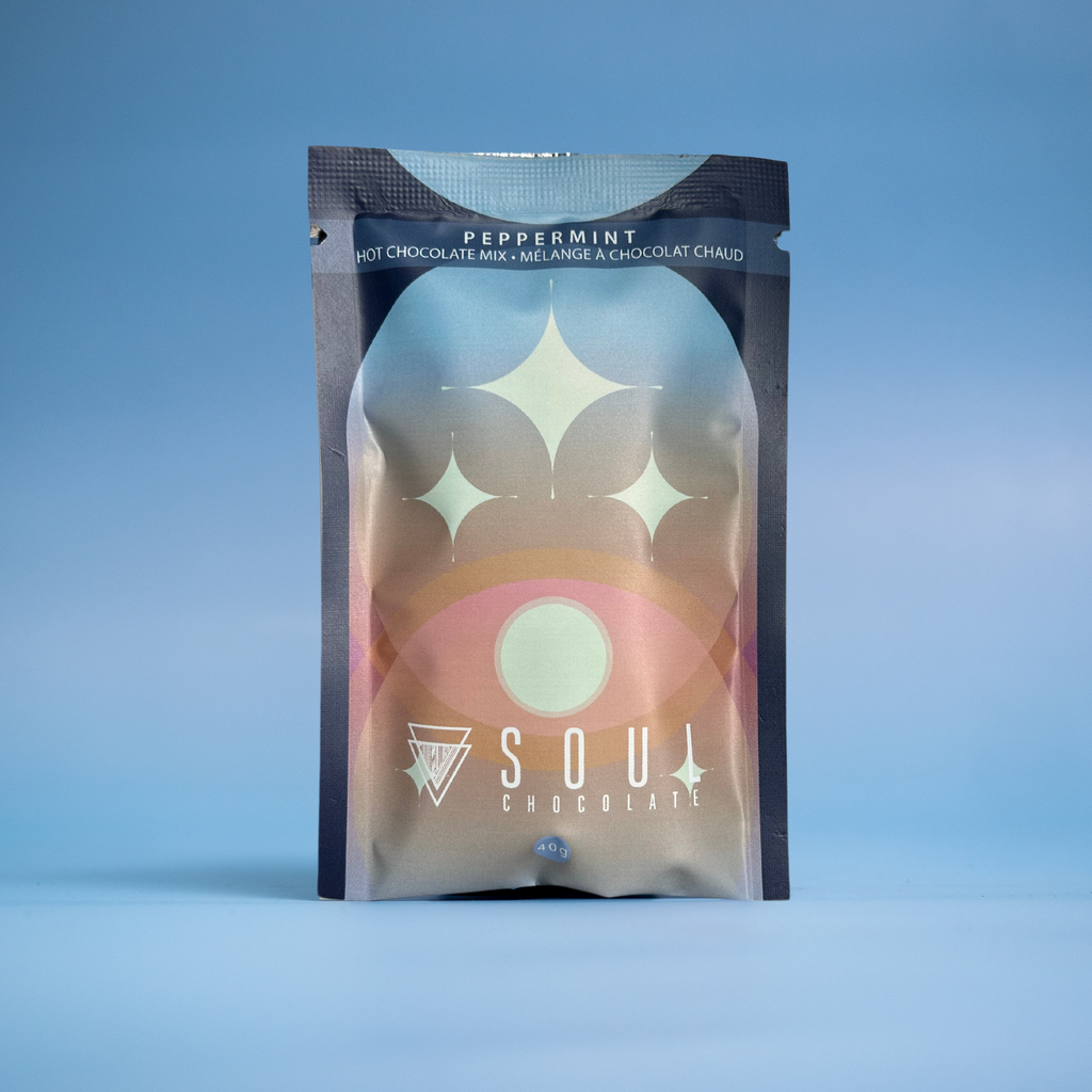 A pouch of peppermint craft hot chocolate mix with a design featuring warm colors and a stylized sun motif. 